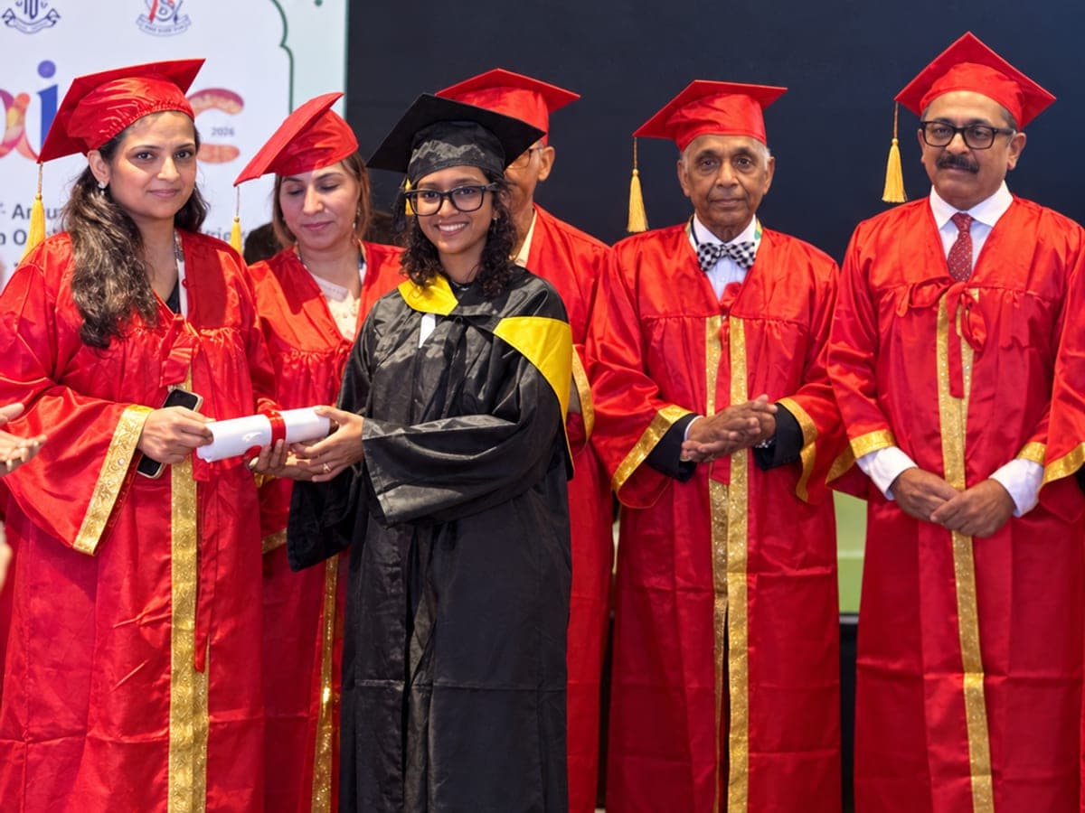 A Ruby Eye Hospital doctor in a graduation gown with faculty in red robes at a convocation